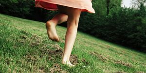 back view of girl running barefoot on a meadow, partial view