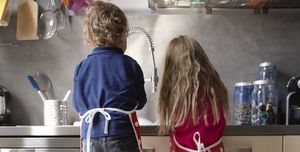 back view of little boy and girl washing dishes in the kitchen