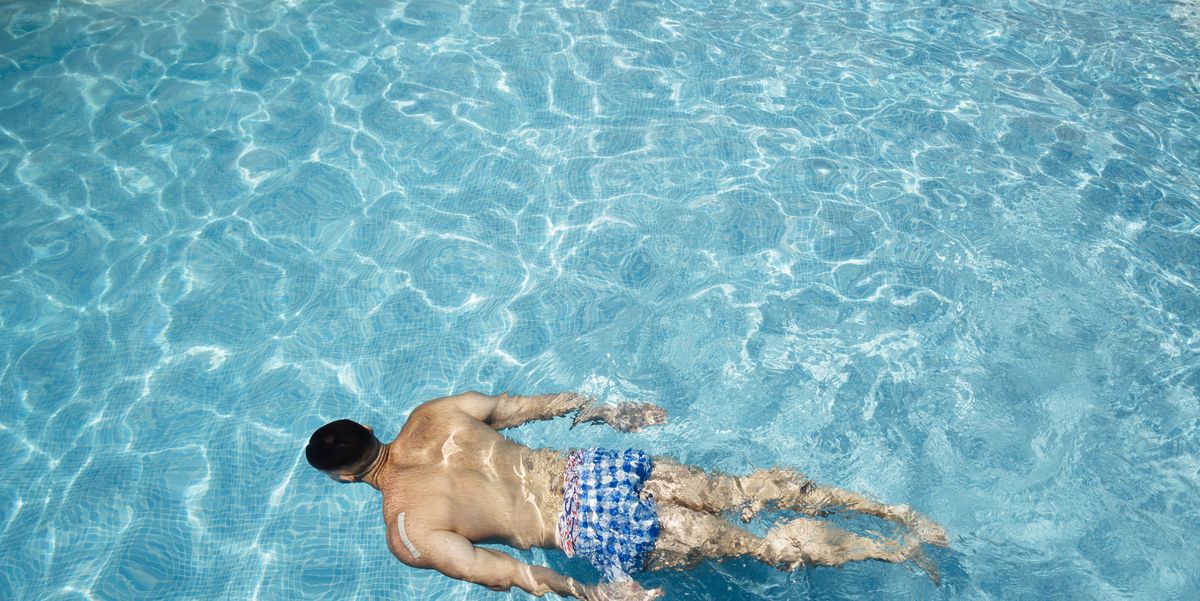 Hombre en bañador de pie junto a la piscina