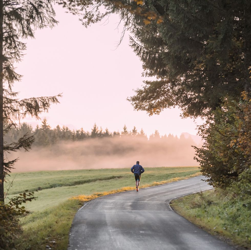 back view of man jogging on country road in the evening