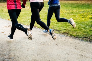 a back view of young athlete legs running on a pedestrian walkway in autumn