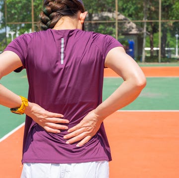 back view of young runner woman suffering from backache or sore waist after running