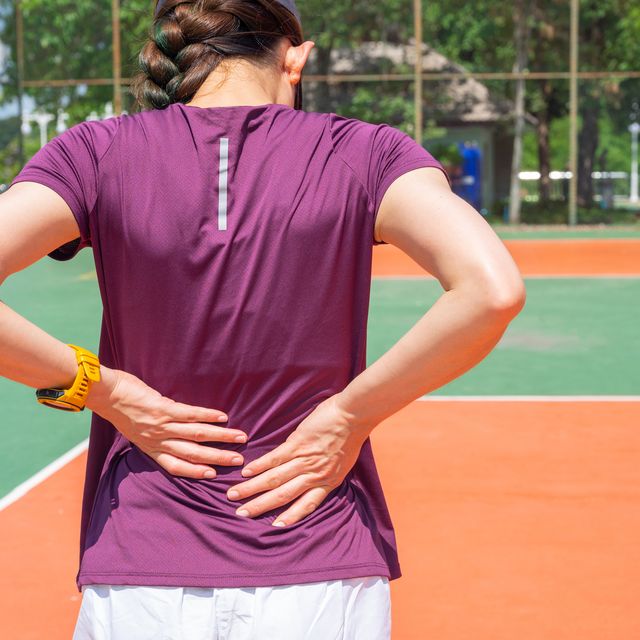 back view of young runner woman suffering from backache or sore waist after running.