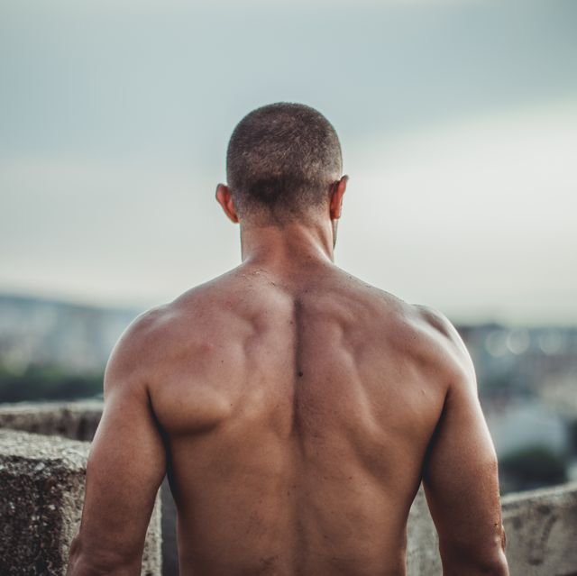 one man, standing outdoors alone, shirtless and very fit, rear view
