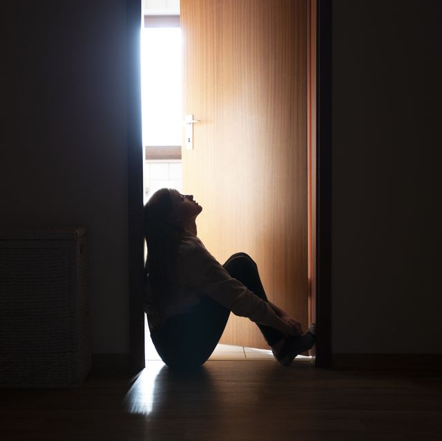 backlit teenager sitting in a dark indoor doorway in contemplation