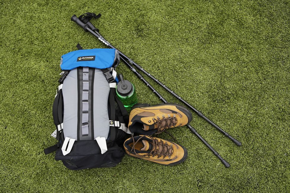 backpack, hiking boots, water bottle and hiking pole on turf