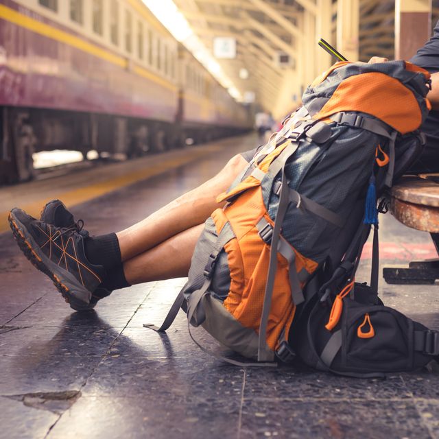 hombre con una mochila en una estación esperando el tren mientras consulta el móvil