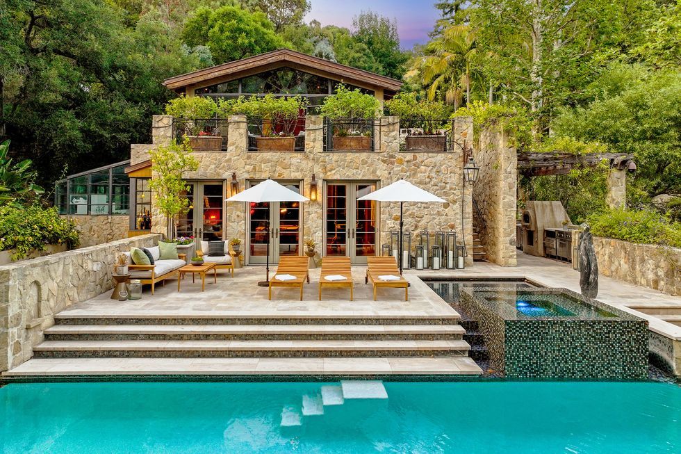 a pool with chairs and umbrellas by a house