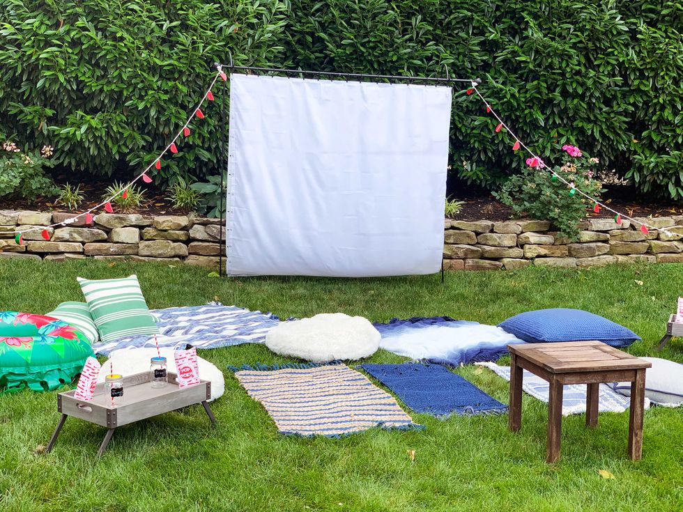 backyard movie night ideas diy movie screen with blankets and pillows set up in the backyard