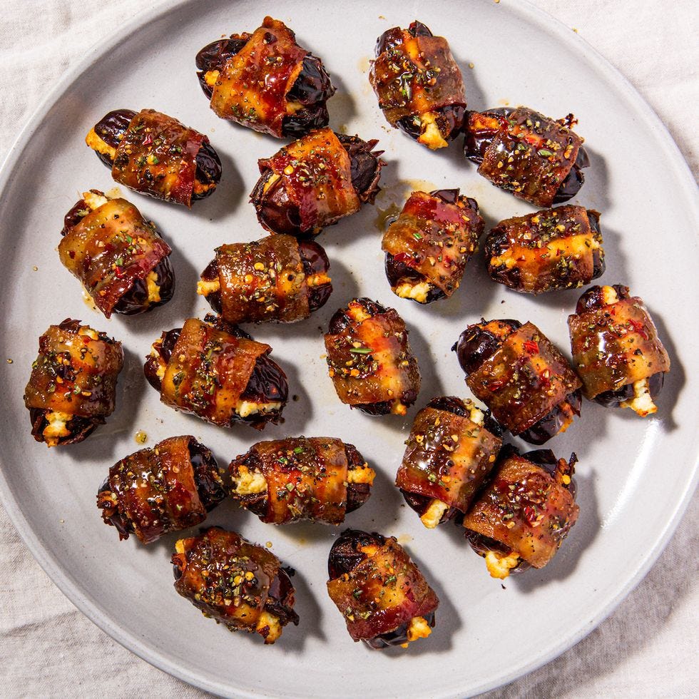 bacon wrapped dates on a white plate