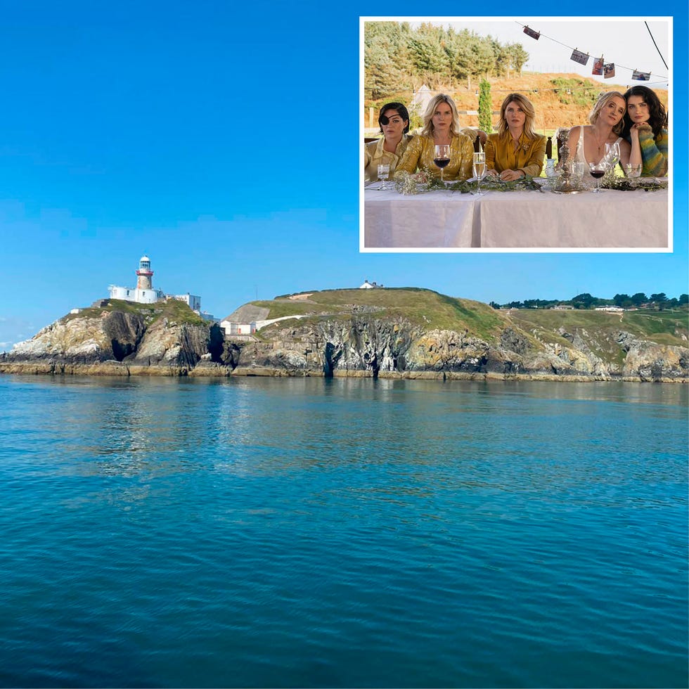 coastal view featuring a lighthouse on a rocky island and a small gathering at a dining table