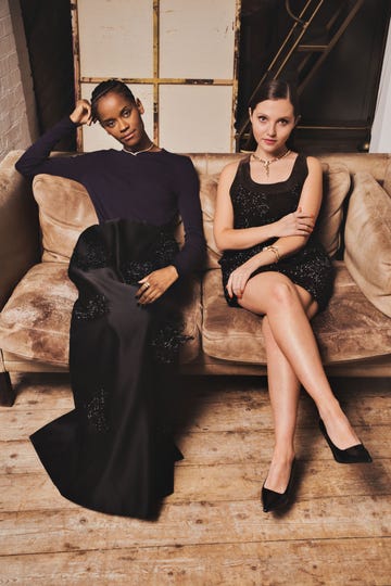 two people seated on a couch each wearing elegant outfits