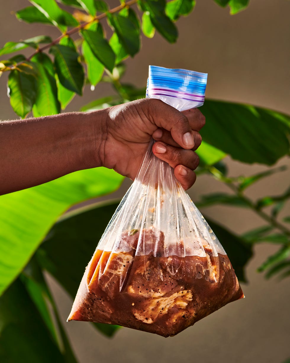 a person holding a plastic bag full of marinating meat