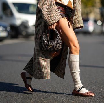paris, france october 04 caroline daur wears a beige and white checkered print pattern wool polo shirt, brown and burgundy shiny leather shorts from miu miu, a beige with brown dark green red houndstooth print pattern oversized long coat, a brown shiny leather embossed handbag from miu miu, beige ribbed wool high socks, brown satin ballerinas , outside miu miu, during paris fashion week womenswear springsummer 2023, on october 04, 2022 in paris, france photo by edward berthelotgetty images