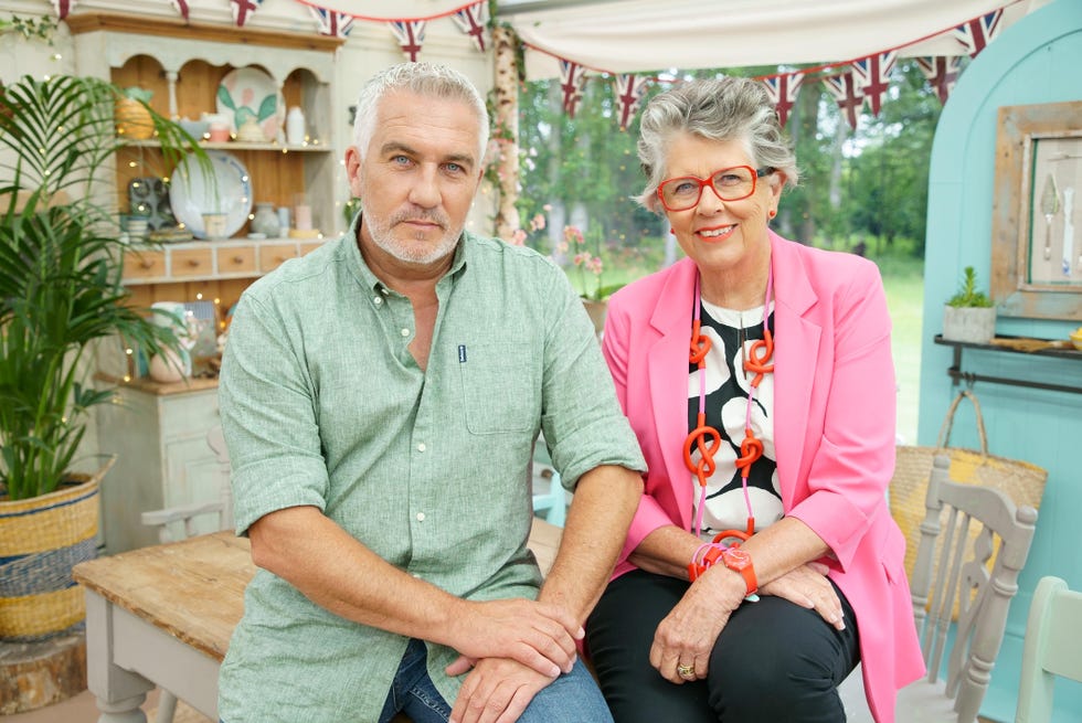 great british bake off judges paul hollywood and prue leith sitting on a table in the tent during the 2021 series