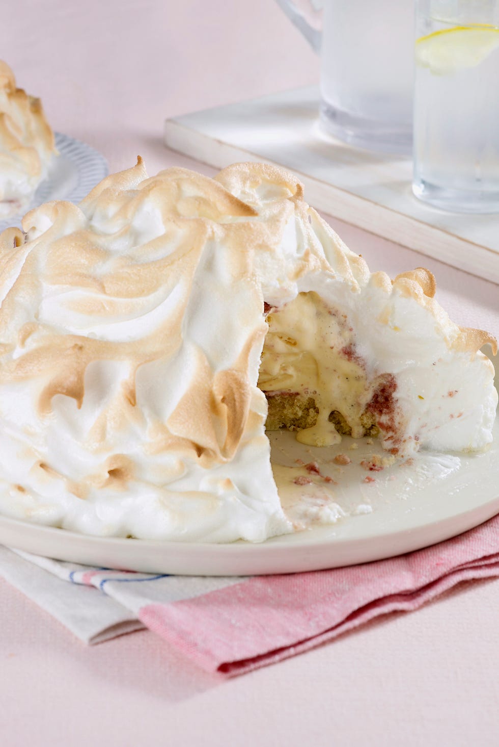 Baked Alaska with slice removed showing ice cream and sponge cake with strawberry Baked Alaska with slice removed showing ice cream and sponge cake with strawberry