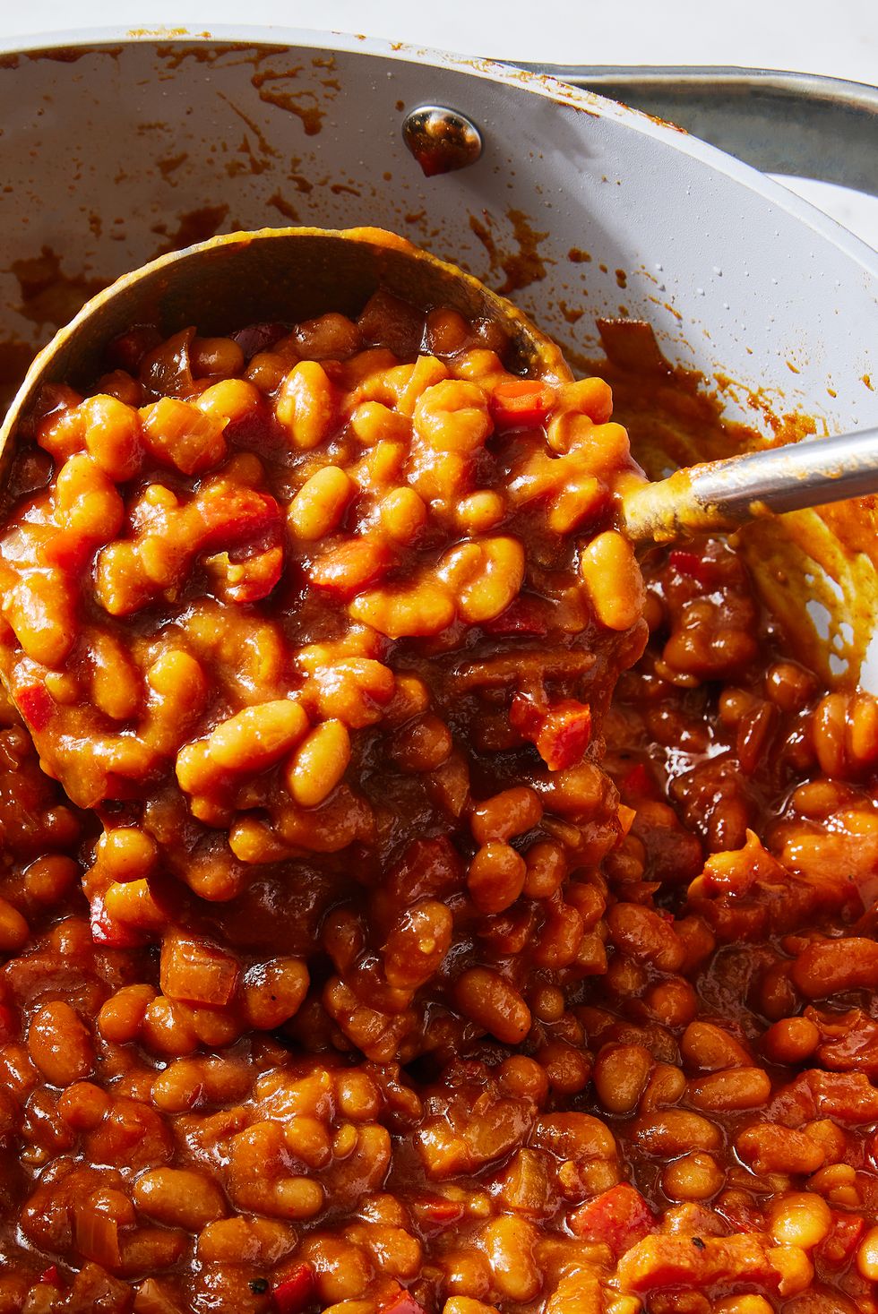 saucy baked beans scooped out of a pot