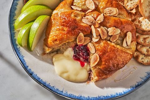 baked brie in puff pastry on a plate surrounded by fruit and crackers