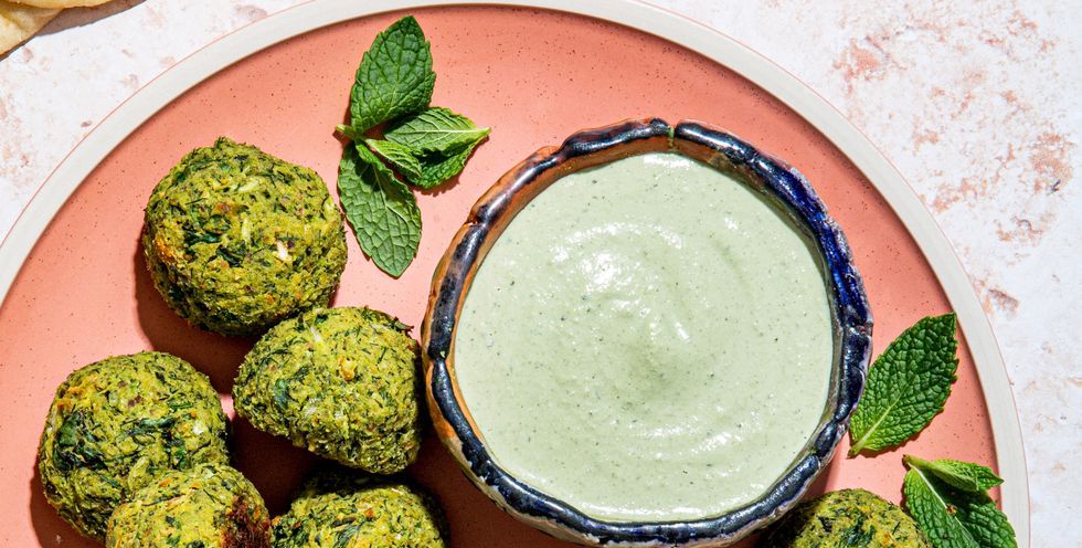 baked green falafel on a pink plate with tahini mint dip and pita