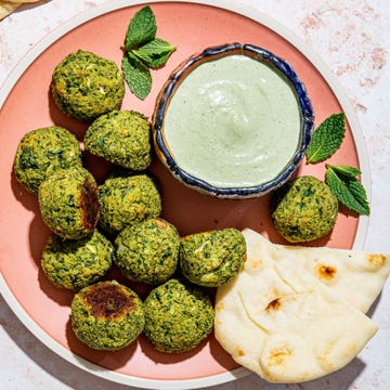 baked green falafel on a pink plate with tahini mint dip and pita