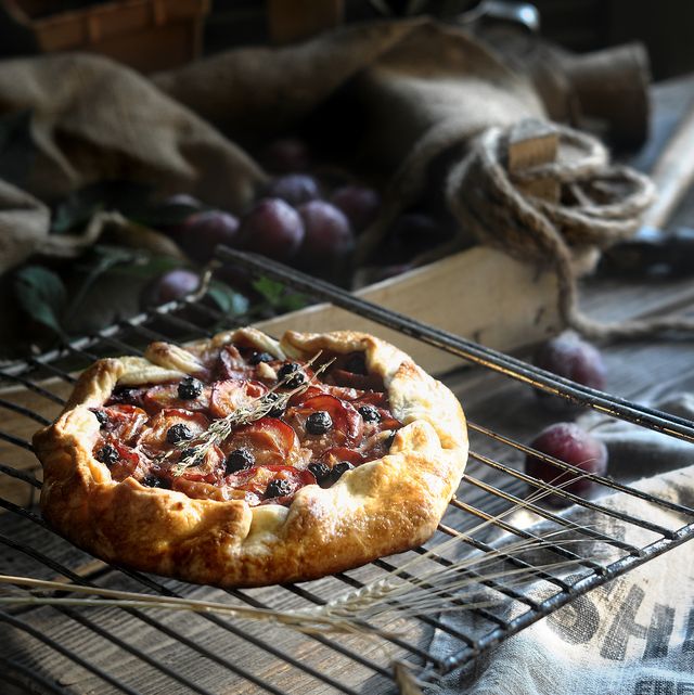 baked open pie or galette with plums and blueberry side view on rustic style interior background closeup selective focus