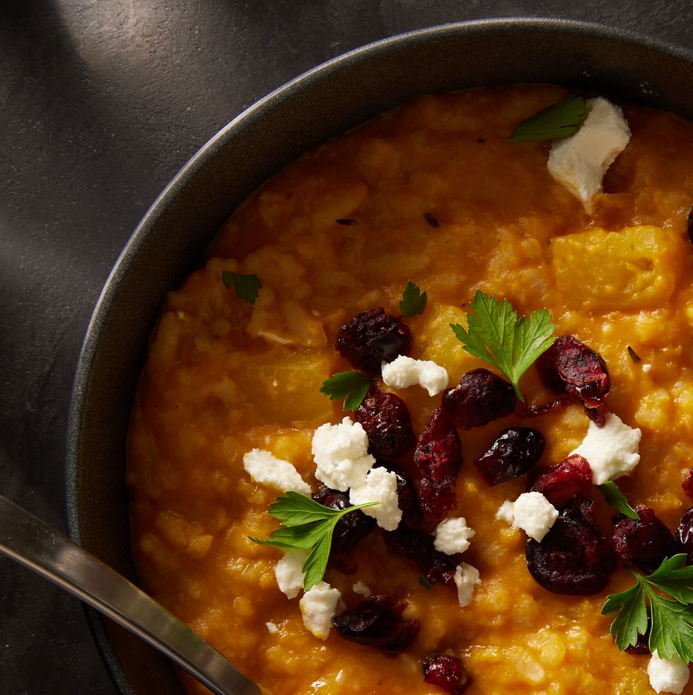 baked pumpkin risotto in a black bowl topped with cheese and dried cranberries