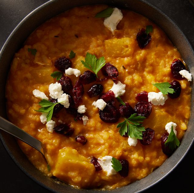baked pumpkin risotto in a black bowl topped with cheese and dried cranberries