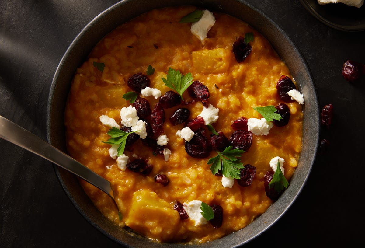 baked pumpkin risotto in a black bowl topped with cheese and dried cranberries