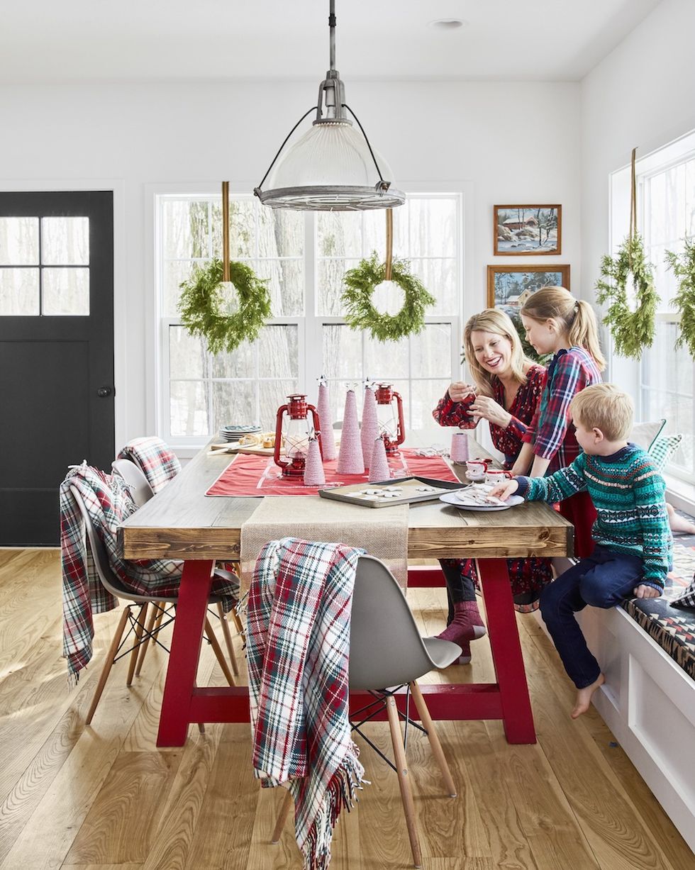 family gathered around kitchen table decorated for christmas with red and white bakers twine christmas trees