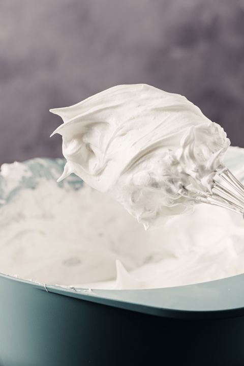 close up of a whisk full of whipped meringues