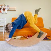 kid playing with balance board in play room
