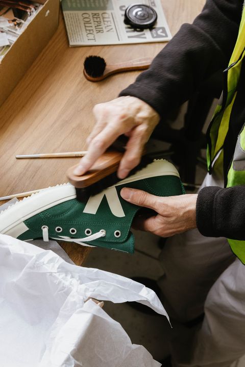 a worker cleans used veja shoes