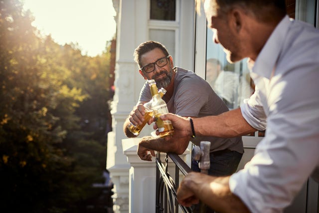 Dos hombres tomando una cerveza en el balcón durante el confinamiento