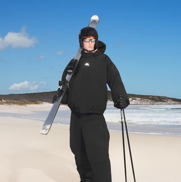 a man holding a pair of skis on a beach