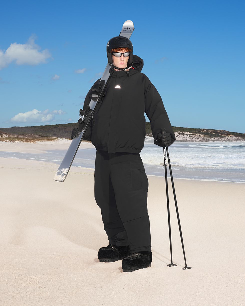 a man holding a pair of skis on a beach