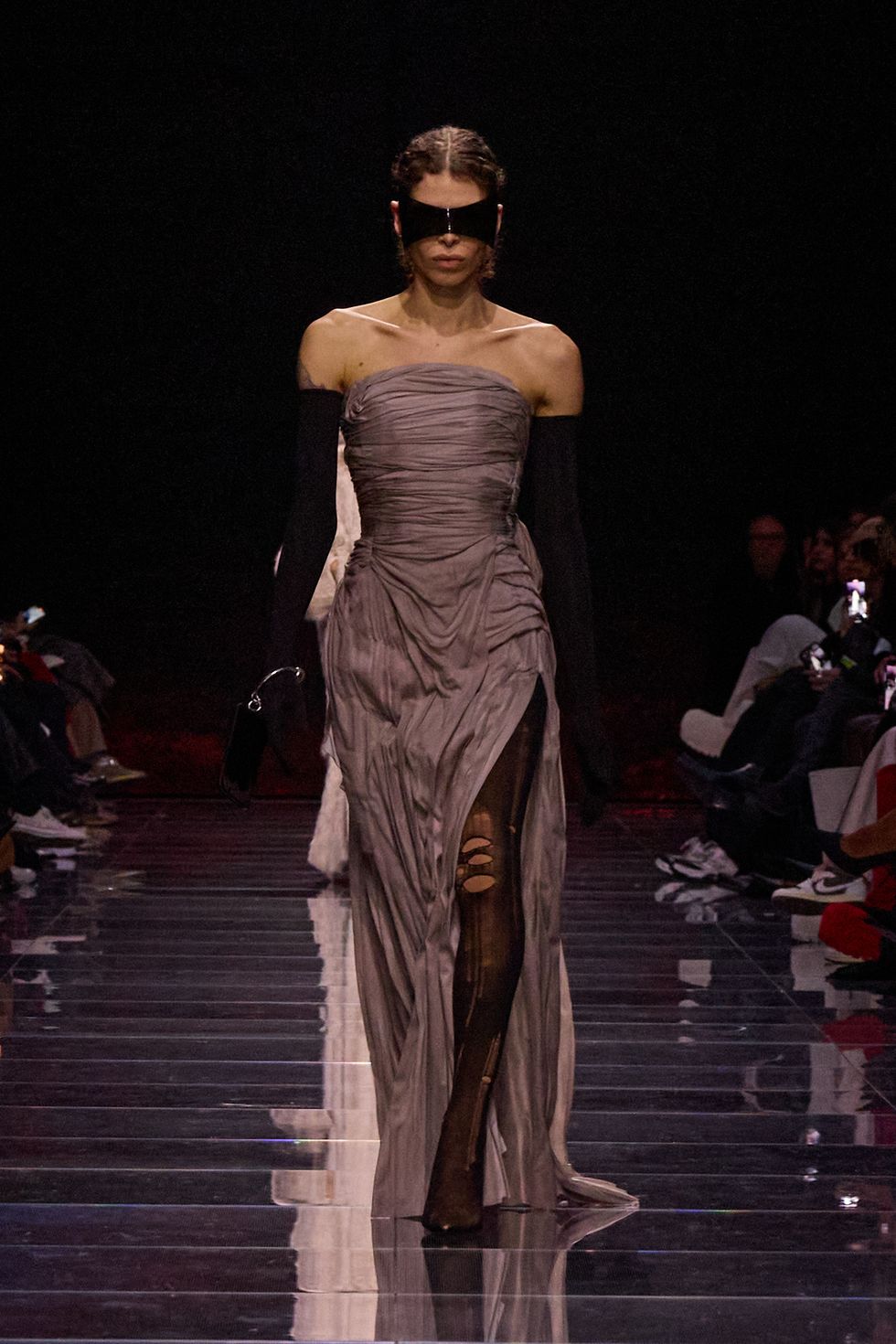 a man wearing a dress and a mask on a runway
