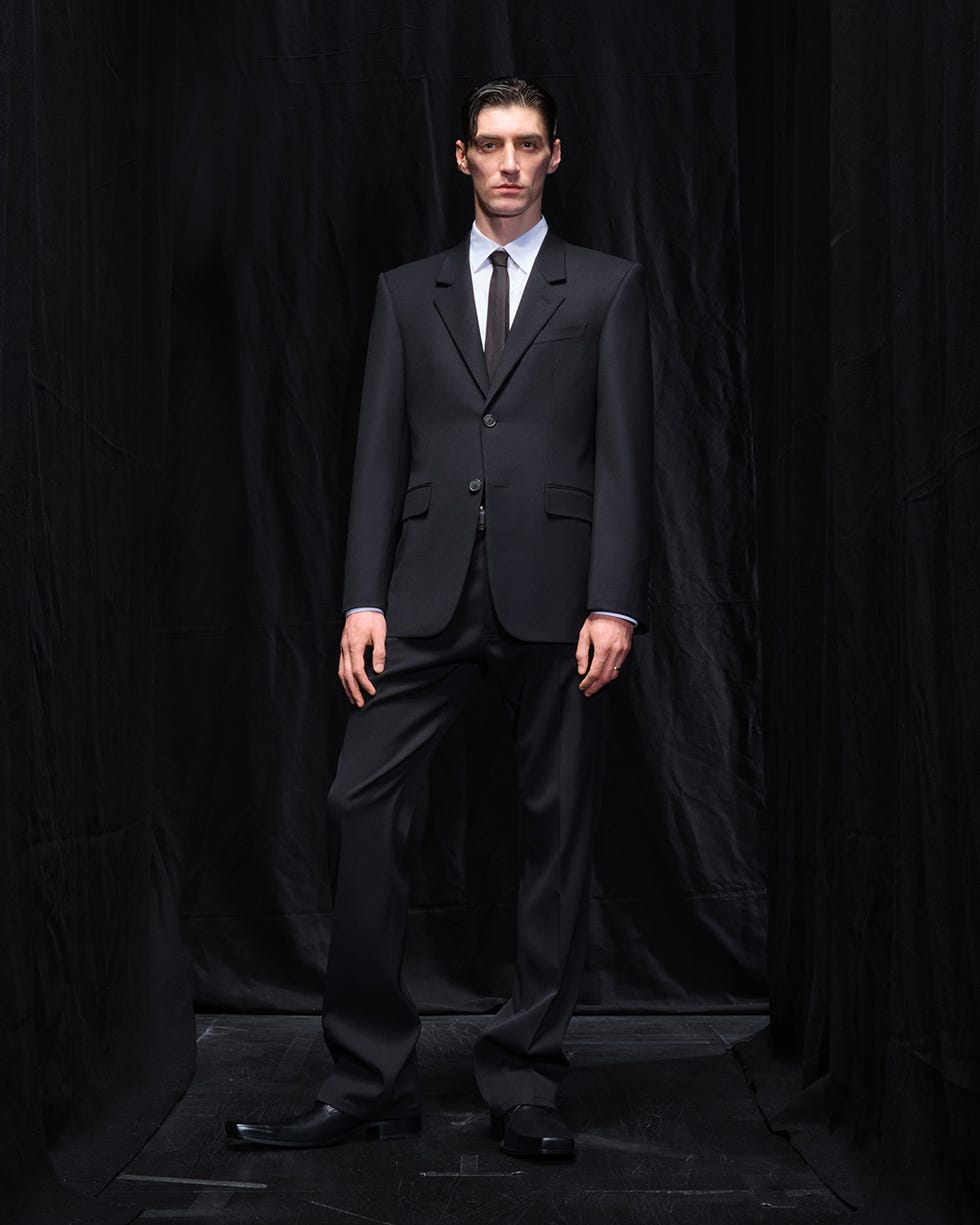 a person dressed in a formal suit standing confidently