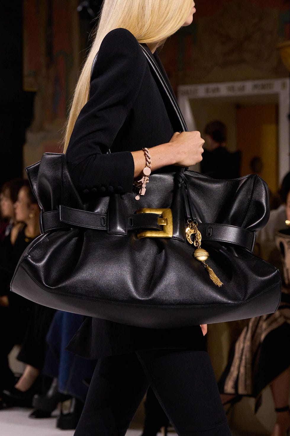 A model walking with a large black handbag