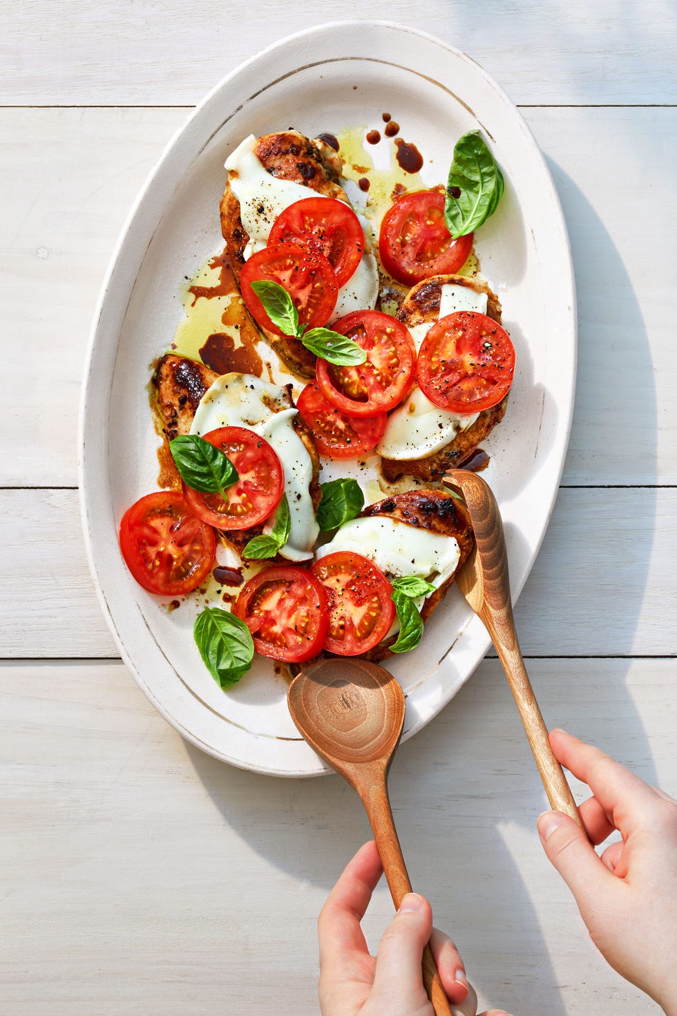 balsamic chicken caprese with mozzarella and tomato on a white plate