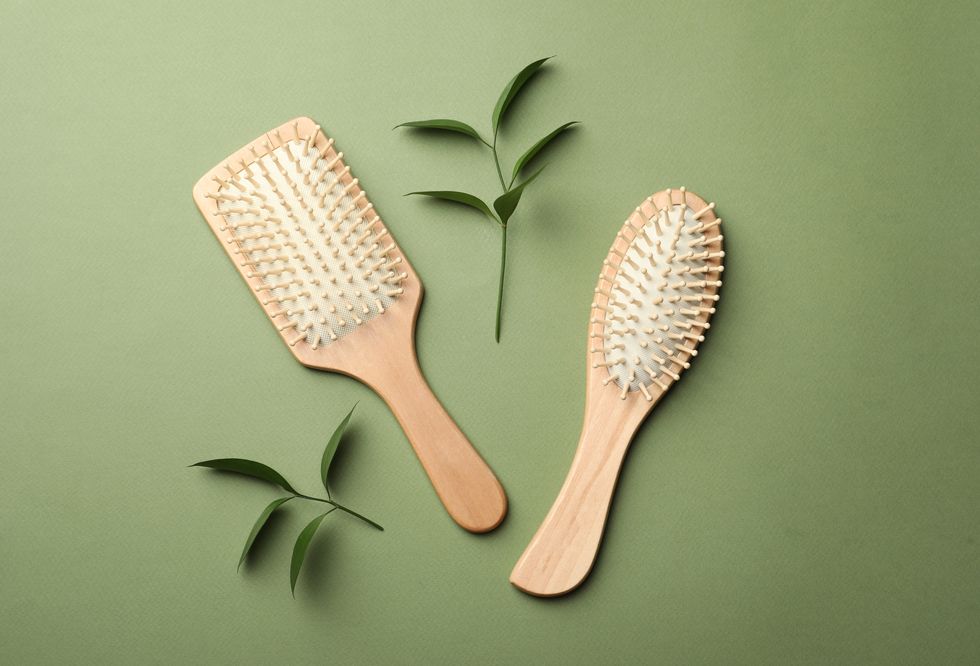 Bamboo hairbrushes on green background, flat lay. Conscious consumption