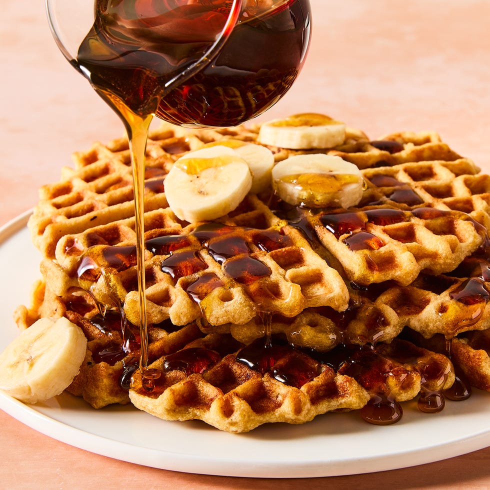stacked waffles topped with banana slices and syrup