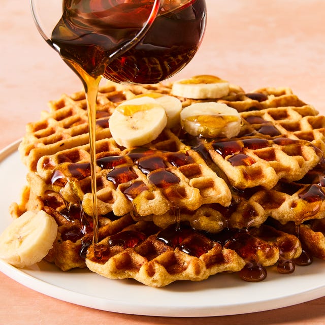 stacked waffles topped with banana slices and syrup