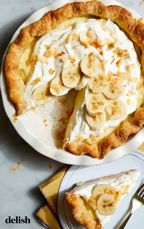 banana cream pie topped with whipped cream, bananas, and toasted coconut flakes