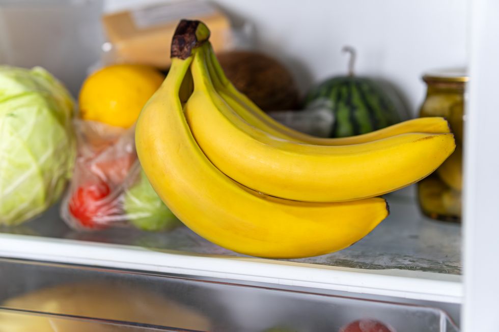 bananas in fridge. yellow bunch of bananas. transparent refrigerator shelf with bananas. plastic fridge drawer.