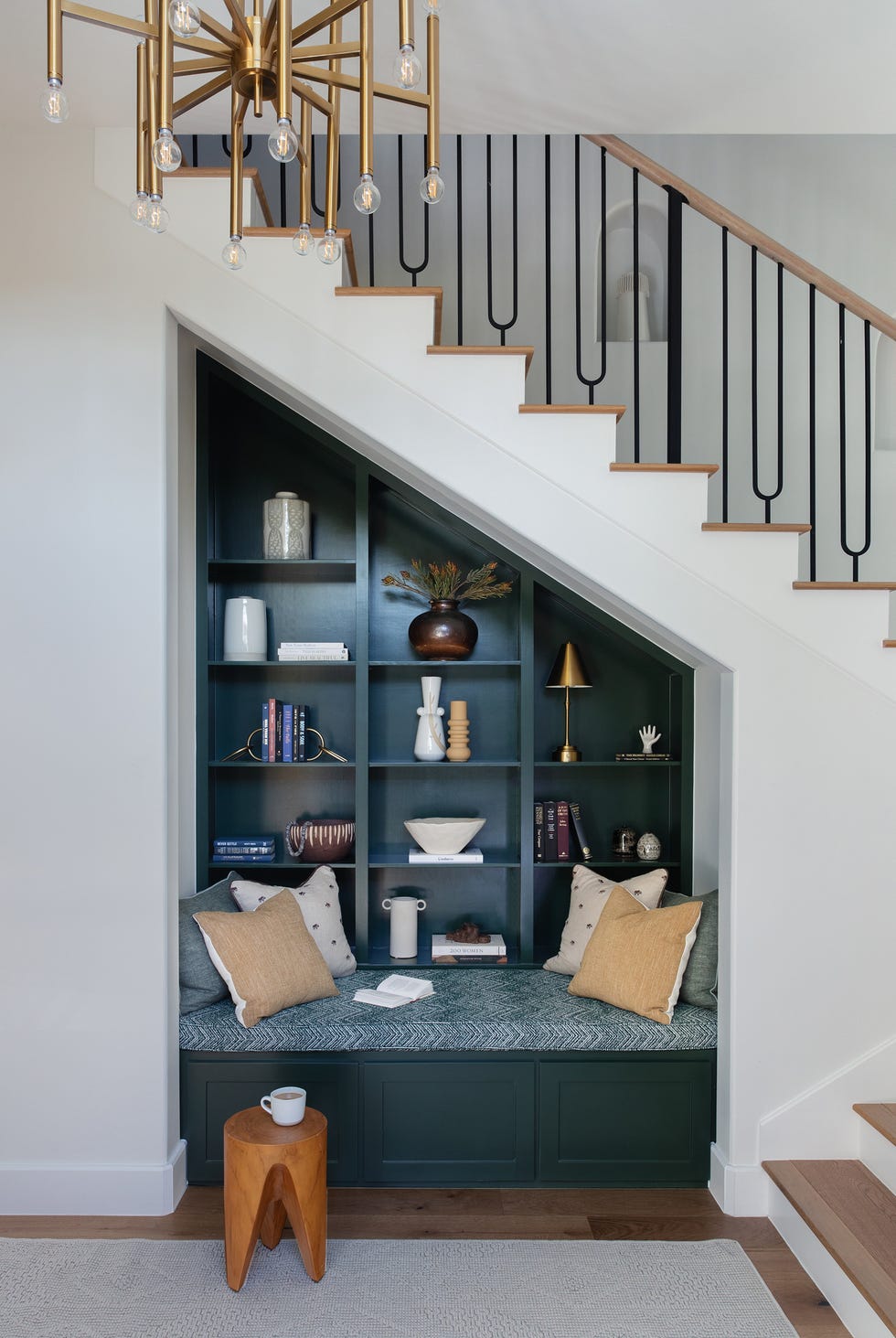 cozy seating area with decorative shelving under a staircase