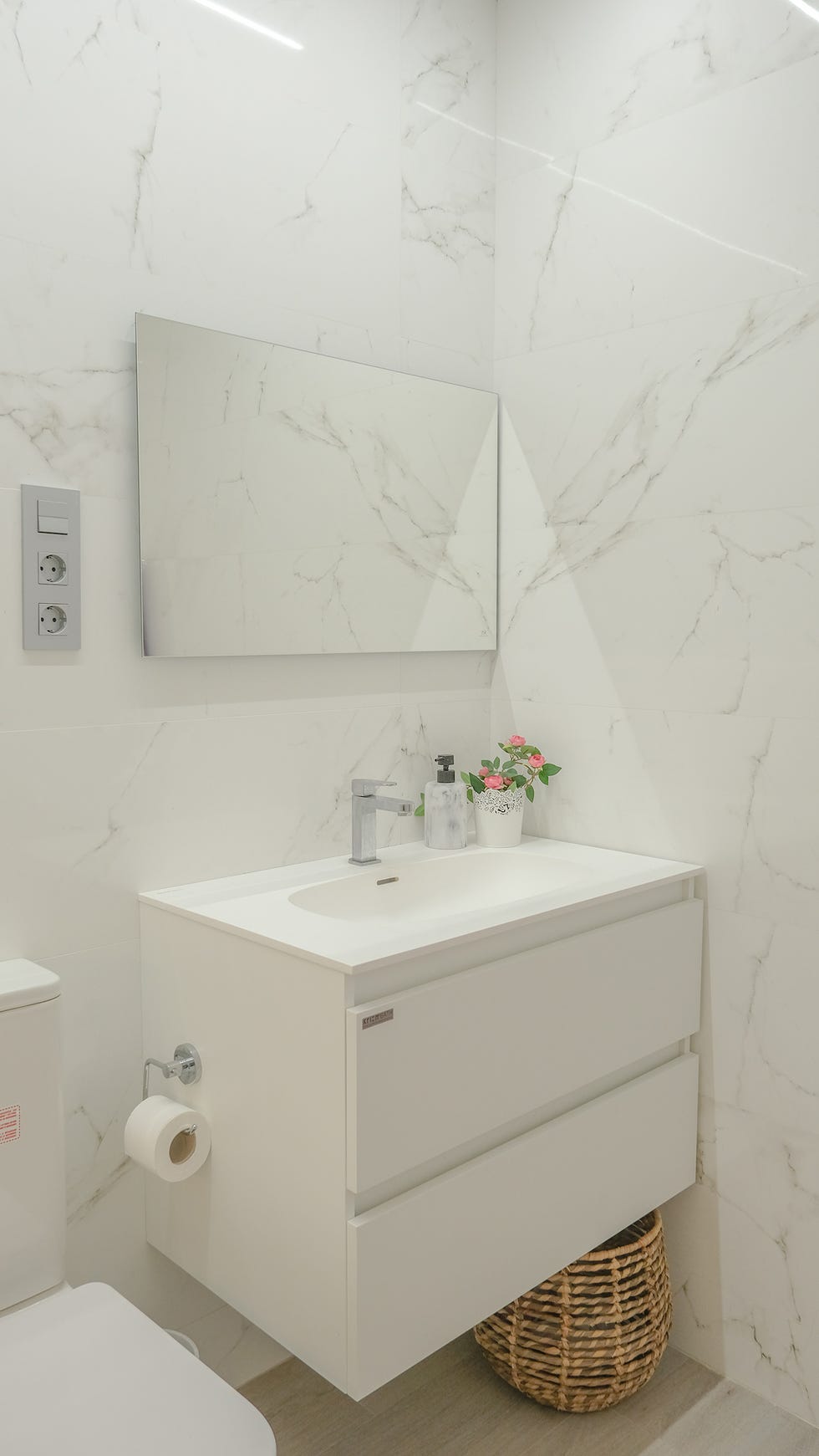 baño con mueble blanco volado y revestimientos de mármol