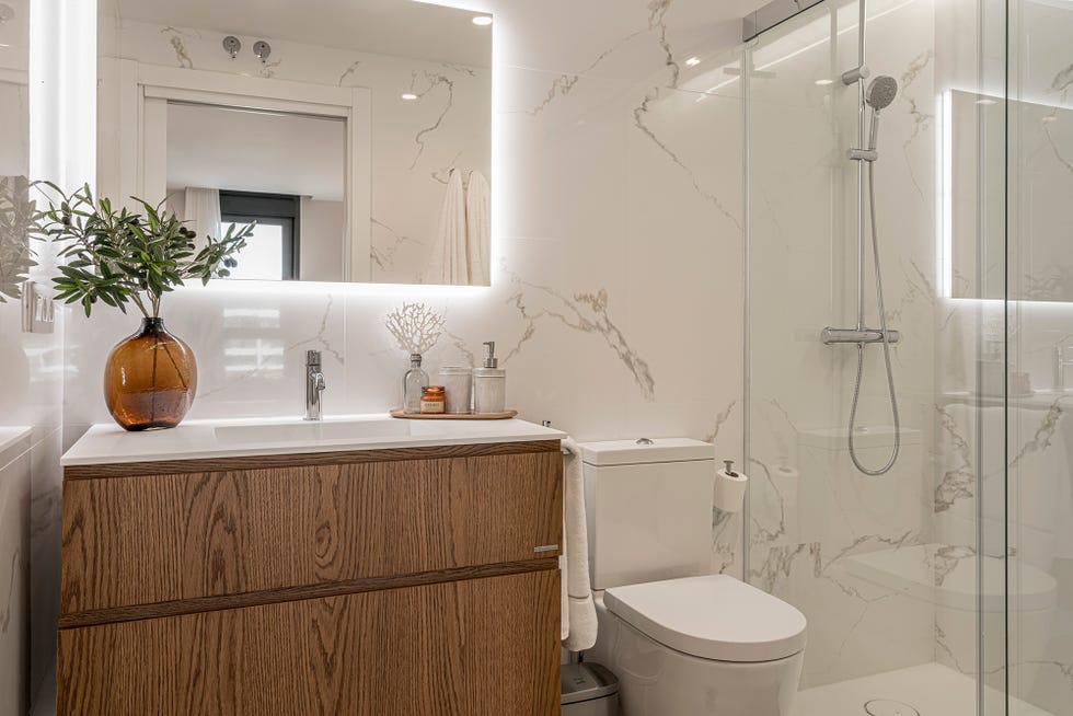 baño con paredes de mármol y mueble de lavabo de madera