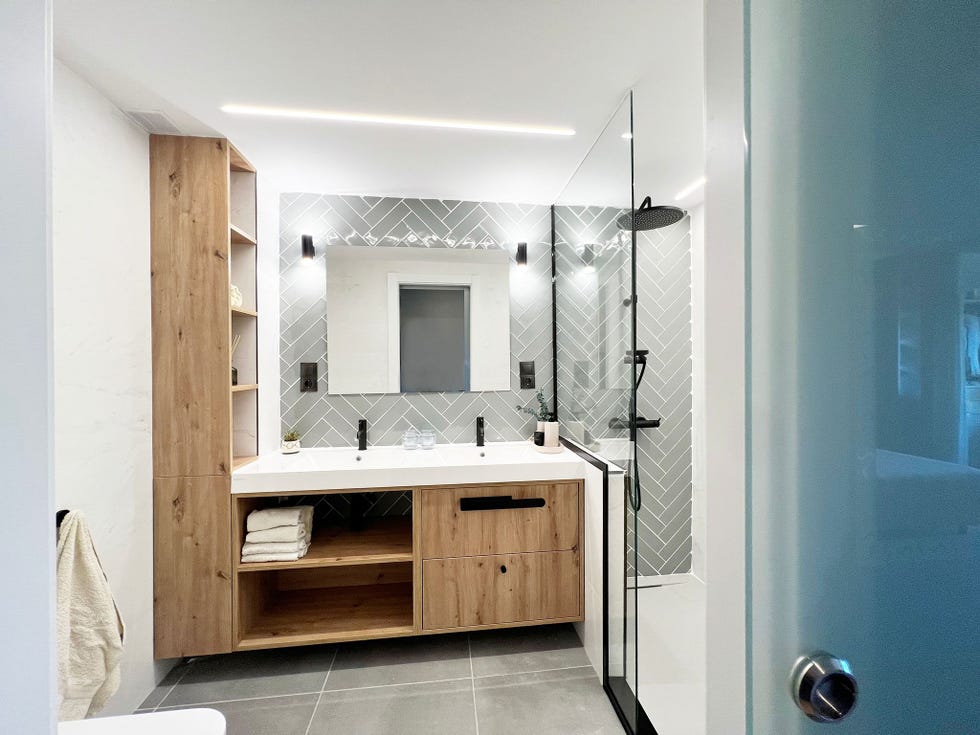 mueble de lavabo de madera y frente de azulejos en espiga que se extienden hasta la ducha