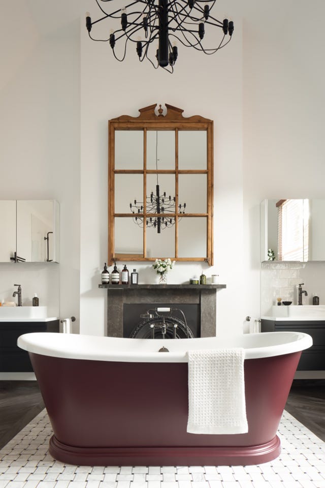 baño de estilo clásico con bañera exenta color vino y chimenea de piedra