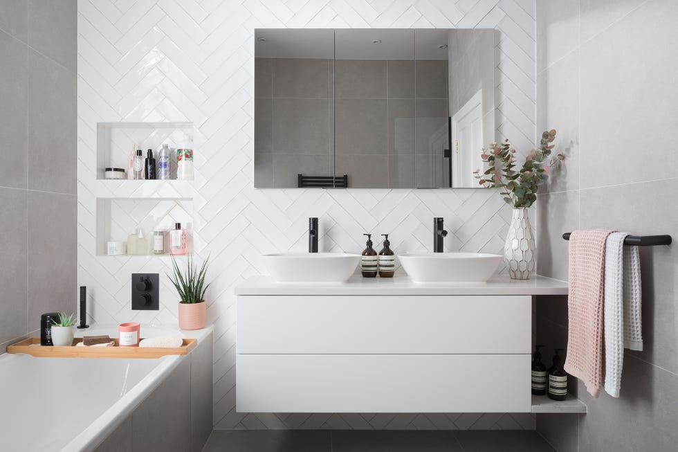 baño decorado en blanco con azulejos de espigas y bañera